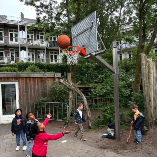 Basketbalpaal Rothe+ 33 In hoogte verstelbare basketbalpaal in gebruik op schoolplein Amsterdam